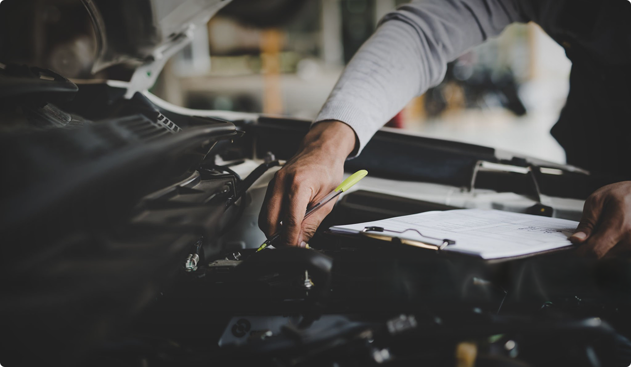 A mechanic working under the hood, logging the service
